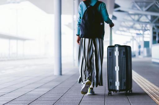 空港でキャリーバッグをもって歩く女性